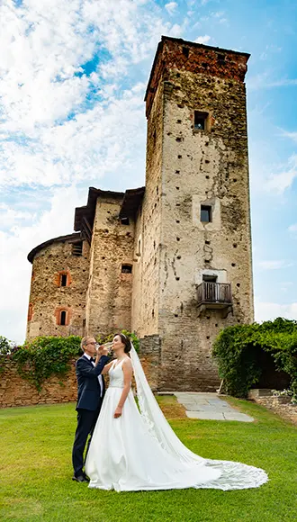 Sposi che brindano nel prato davanti al castello medievale di Bagnolo