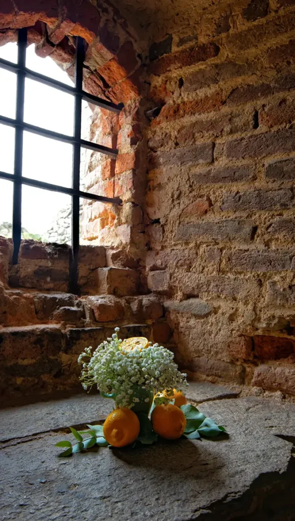 Finestra con inferriata metallica inserita in muratura in pietra e laterizio del Castello medievale.