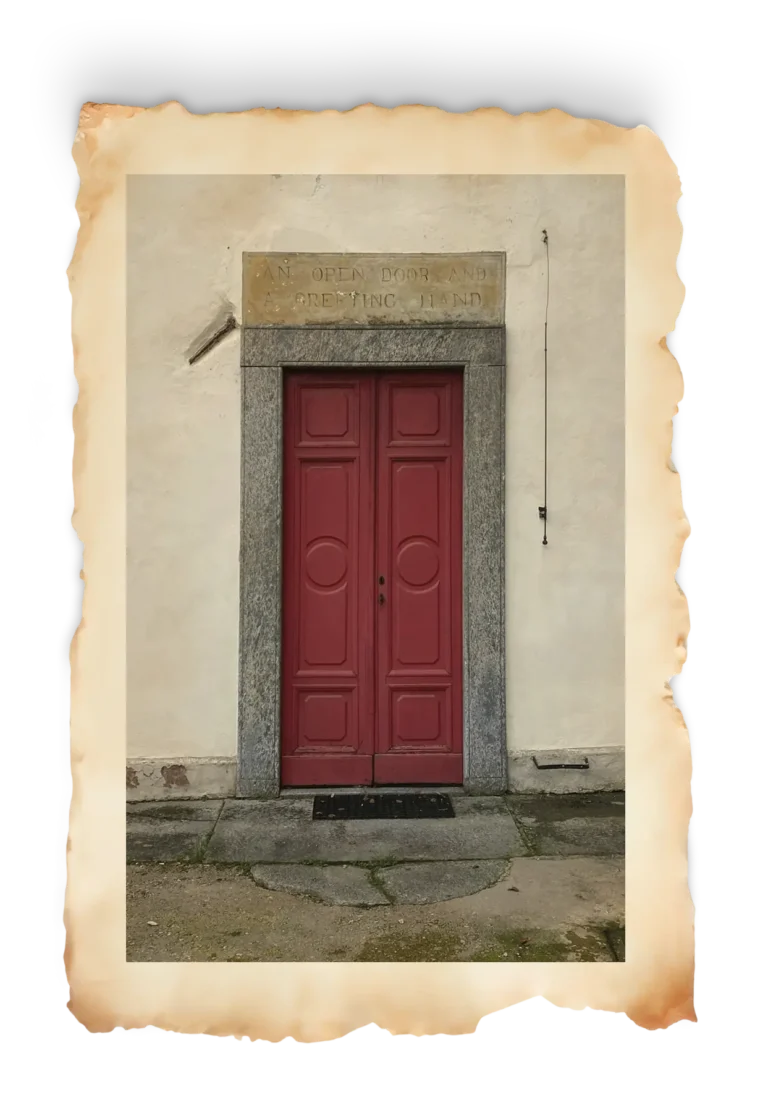 Porta rossa con iscrizione “An open door and a greeting hand” nel cortile del Castello di Bagnolo