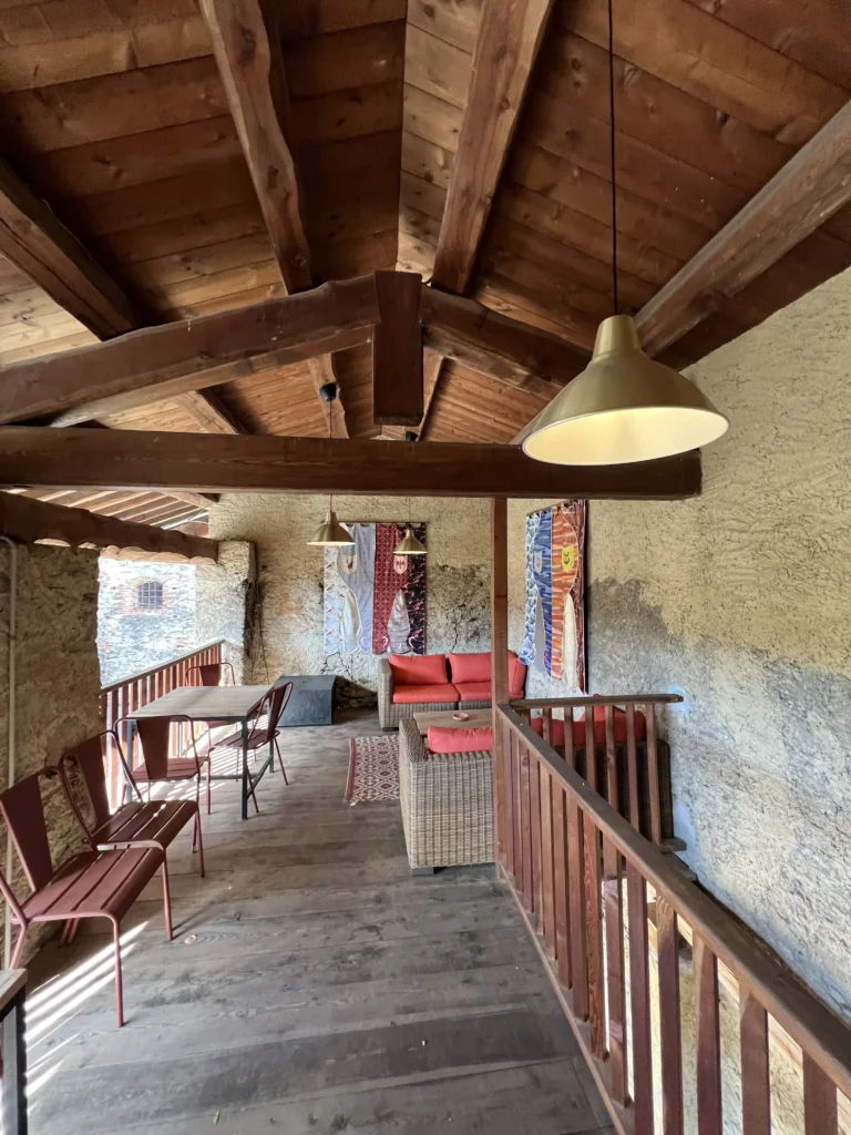 Loggia con travi in legno e tavoli della cascina utilizzata per incontri informali durante eventi aziendali